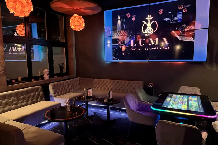 Samtsofas und Lampions vor der LUMA-Videowand